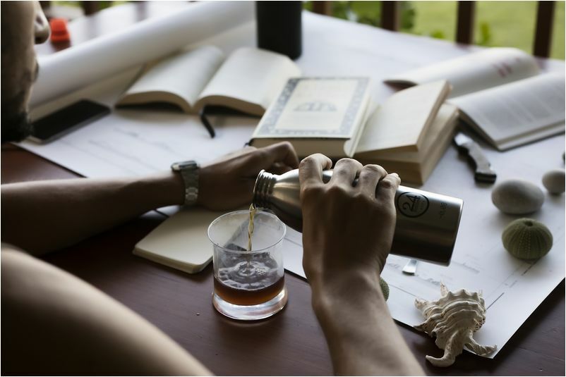 férfi könyvekkel teli asztalon design termosz kulacsból italt tölt a poharába, ajándék ötletek férfiaknak