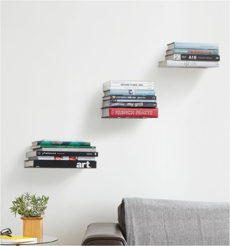 szürke kanapé fölött falon elhelyezett lebegő könyvespolcok egymásra fektetett könyvekkel amik így lebegő hatást keltenek, ajándék ötletek férfiaknak