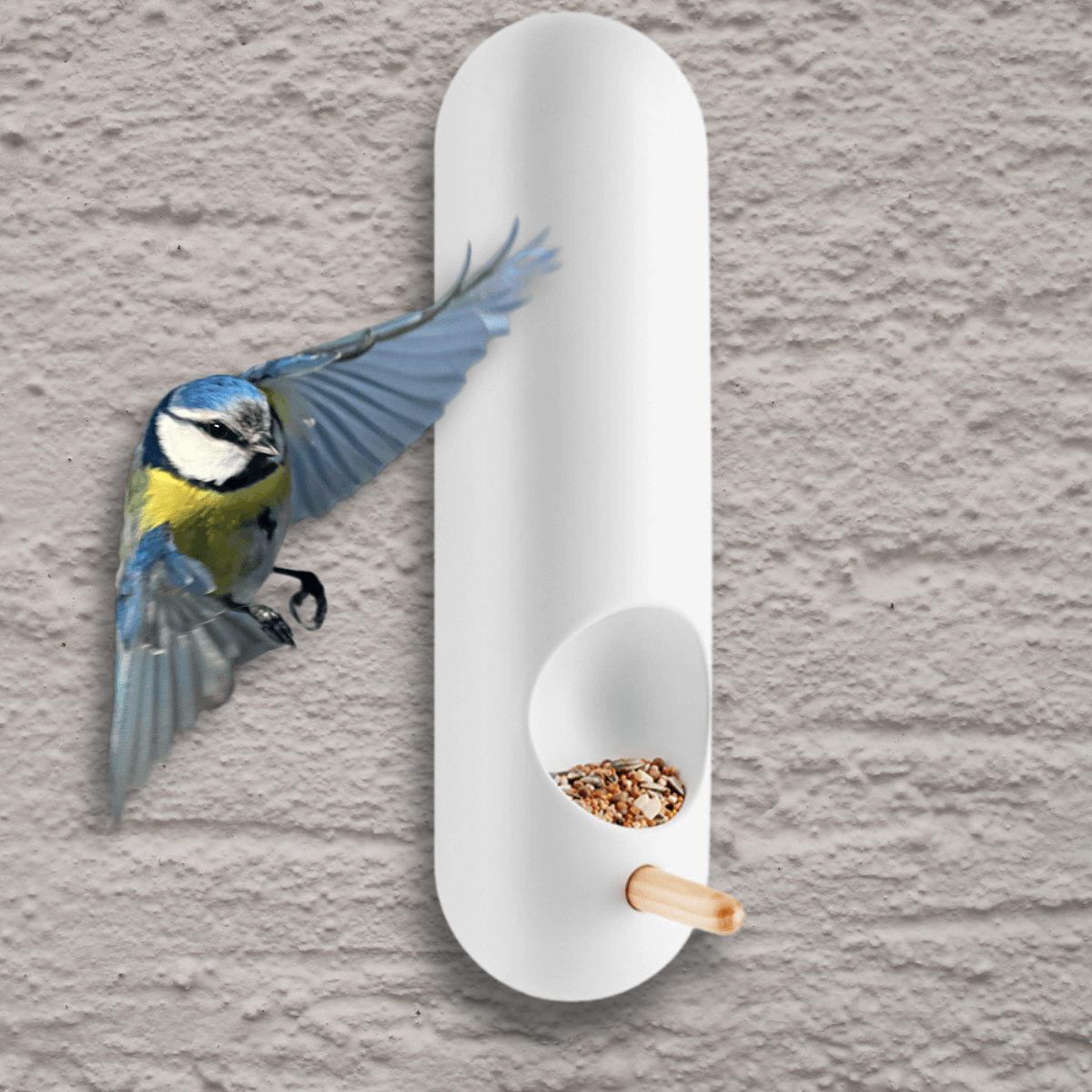 falra rögzíthető, hosszúkás cső alakú fehér madáretető amire cinege készül landolni